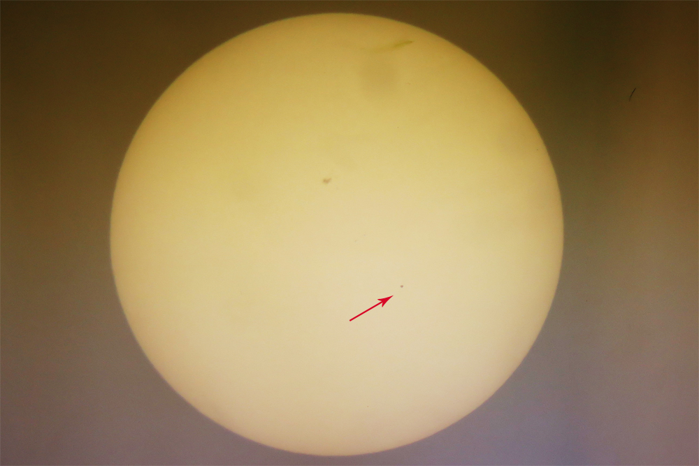 Merkur přecházející přes Slunce (droboučká tečka, na niž ukazuje šipka) pozorovaný z třebíčské hvězdárny dnes kolem půl páté odpoledne. Flíček nad středem plochy je sluneční skvrna.