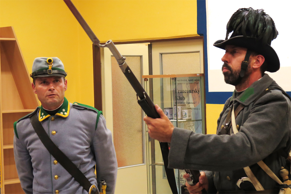 Josef Michalík s Jaroslavem Baštou předvádějí uniformy a zbraně, které naši vojáci používali během bitvy u Hradce Králové.